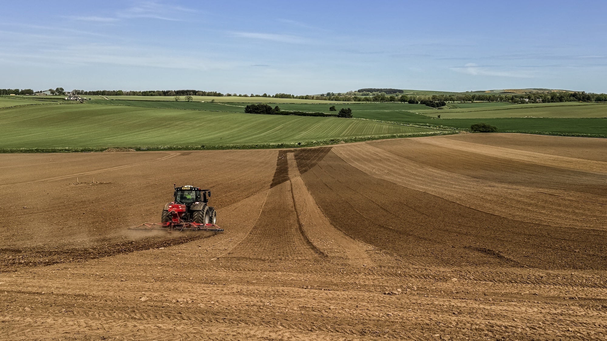 Tractor plowing a field in Scotland with a clear blue sky to prepare for sowing wildflower seed. To highlight grass seed agricultural, agricultural grass seed, british wild flower seeds, british wildflower seeds, wildflower mixes, amenity lawn seed, lawn seed, grass lawn seed.